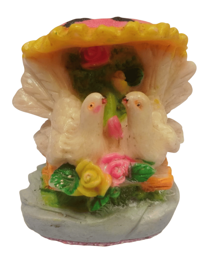 A beautiful showpiece of two white doves sitting on a branch with a pink umbrella.