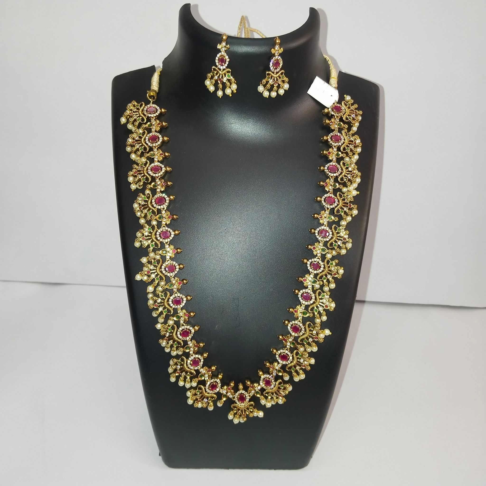 Gold-plated traditional long haram necklace set with ruby and emerald stones and matching earrings for women